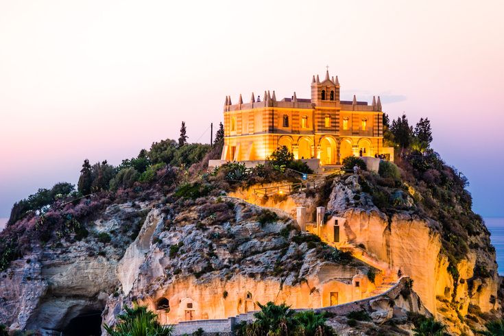 Eine Burg auf einem felsigen Hügel bei Sonnenuntergang.