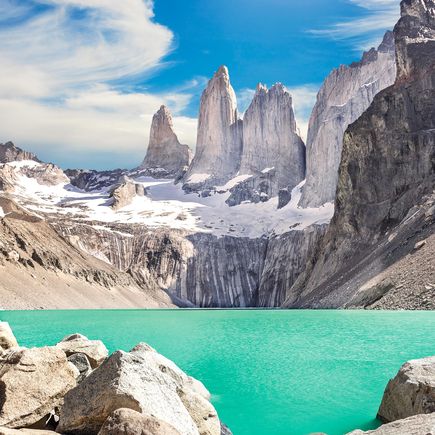 Die markanten Granitfelsen der Torres del Paine in Patagonien, Chile, ragen majestätisch in den Himmel und spiegeln sich in einem See im Vordergrund wider.
