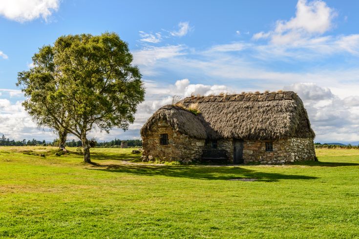 Blick auf ein Steinhaus in Culloden Battlefield, sehr ruhig gelegen und nur umgeben von einem Baum und einer saftigen Wiese.