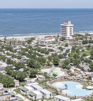 Ferienanlage mit zahlreichen Mobilheimen, Pool und direkter Strandlage an der Küste mit Blick auf das Meer.