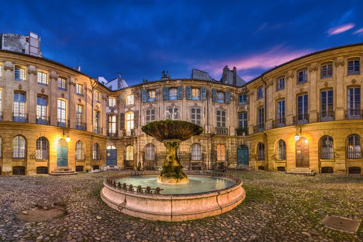 Blick auf den Brunnen in Aix en Provence. Dahinter ein altes Gebäude.