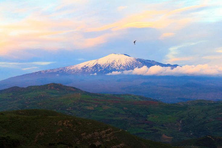 Eine Berglandschaft mit Wolken und einem Tal bei Sonnenuntergang.