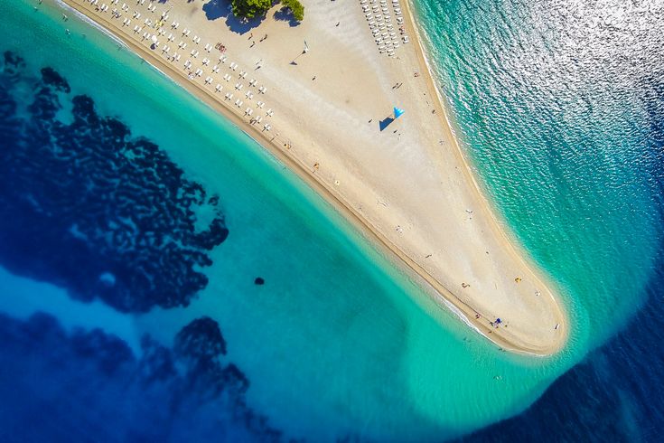 Ein Sandstrand mit türkisfarbenem Wasser.
