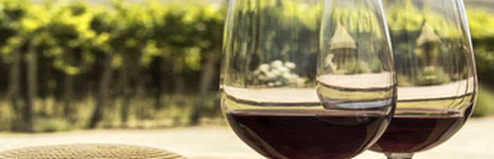 Ein Glas Rotwein auf einem Tisch in einem Weinberg.