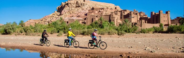 Drei Personen fahren Fahrrad durch eine orientalische Landschaft