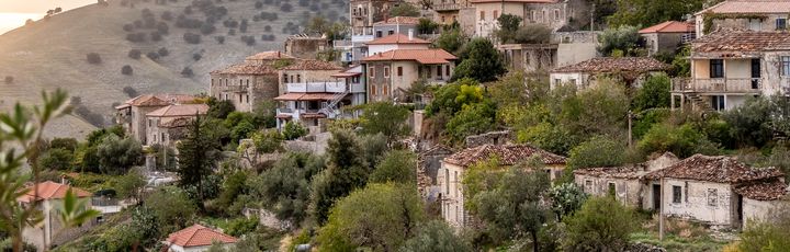 Sonnenbeleuchtete Dorfansicht alter Steinbauten am Hang, Qeparo, Qark Vlora