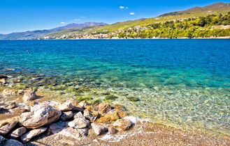 Ein Sandstrand mit türkisfarbenem Wasser und einer Küstenlinie.