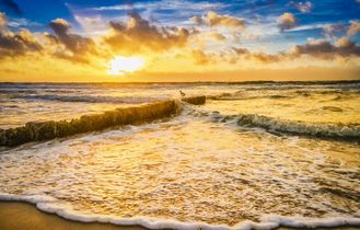 Strand mit Wellen bei Sonnenuntergang.