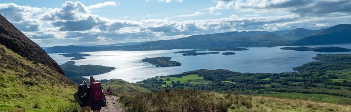 Blick auf das weitläufige Loch Lomond. Wanderer sind ebenfalls zu sehen.