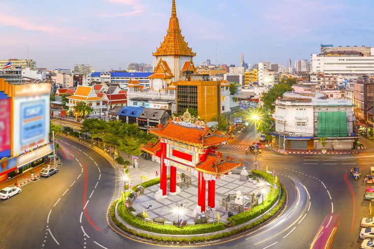 Das hell erleuchtete chinesische Tor am Odeon Circle in Bangkoks Stadtteil Chinatown bei Dämmerung.