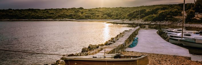 Eine Landschaft mit einem Fluss oder See und einer Brücke bei Sonnenuntergang.