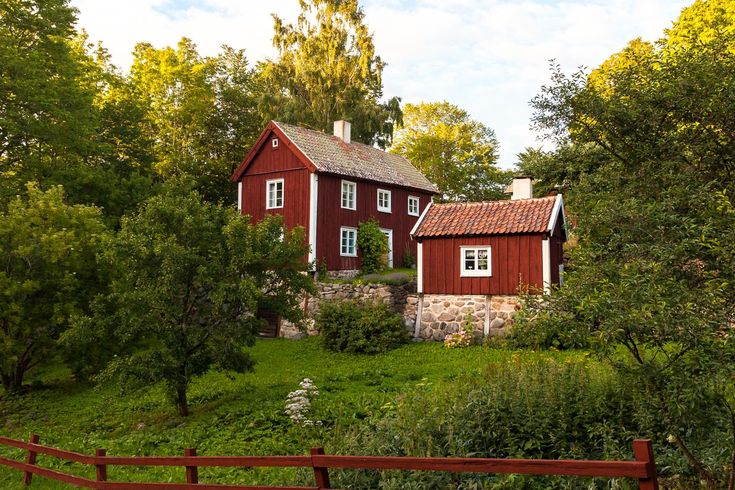 Traditionelles rotes schwedisches Haus mit weißen Fensterrahmen und grünem Garten.