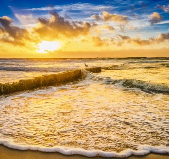 Strand mit Wellen bei Sonnenuntergang.