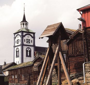 Eine alte, traditionelle Stabkirche in Norwegen, umgeben von grüner Vegetation.