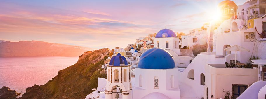 Eine malerische Ansicht der Insel Santorin, Griechenland, mit ihren charakteristischen weißen Häusern, blauen Kuppeln und dem weiten, blauen Meer bei Sonnenuntergang.