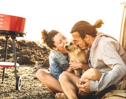 Ein Paar sitzt gemütlich mit ihrem Hund an einem Tisch im Freien, entspannte Atmosphäre.