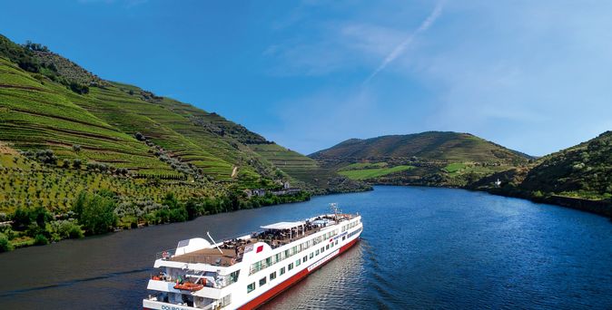 Kreuzfahrtschiff fährt durch das Meer mit grünen Bergen im Hintergrund