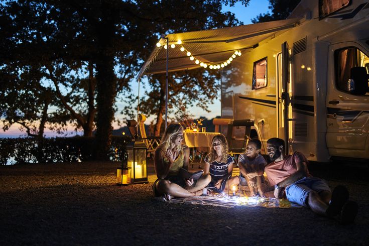 Eine Familie vor einem Camper bei Nacht