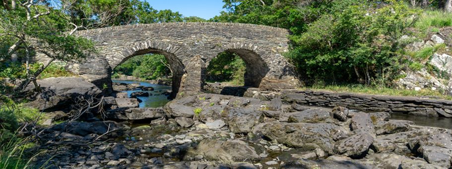Eine alte Steinbrücke, die über einen Fluss führt.