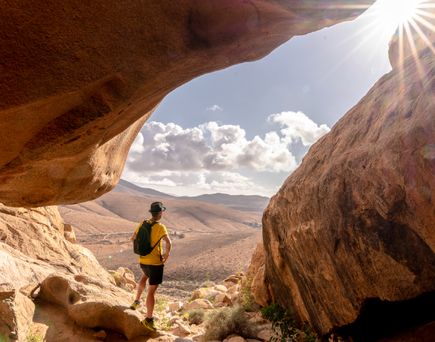 Wanderer steht auf Fuerteventura und blickt in die Ferne in die Sonne.