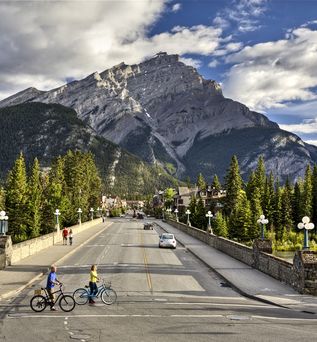 KAnadische Straße die auf einen Berg zu lauft. Im Vordergrund Radfahrer