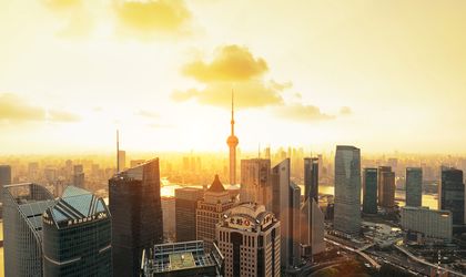 Die beeindruckende Skyline von Shanghai bei Sonnenaufgang, mit zahlreichen beleuchteten Wolkenkratzern und einem Fluss im Vordergrund.