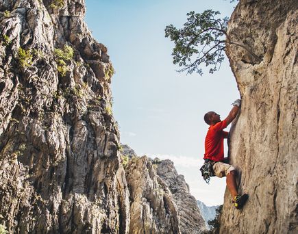 Eine Person klettert an einem Felsen hinauf.