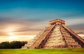 Eine Maya-Pyramide in einer weiten Landschaft bei Sonnenuntergang.