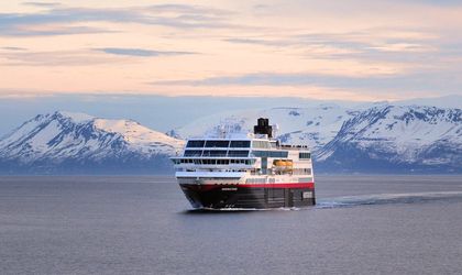 Die MS Midnatsol im Vordrgrund, auf dem Waser. im Hintergrund die eis- und schneebedeckten Berge.