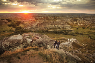 Motorradfahrer Paar schaut auf in den Sonnenuntergang im Dinosaur Provincial Park in Alberta
