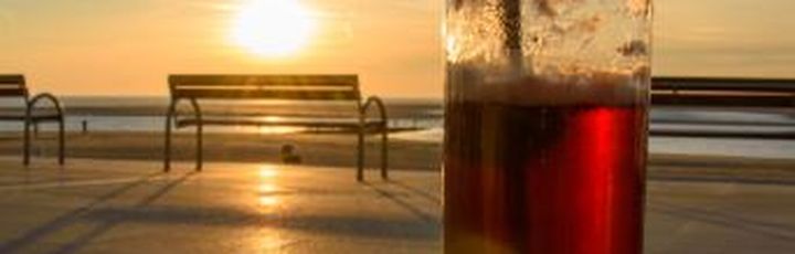 Ein Getränk am Strand bei Sonnenuntergang.
