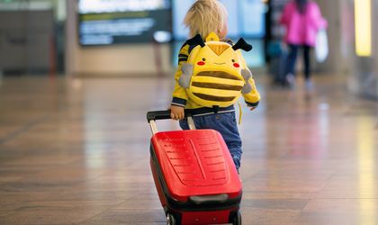 Kind geht mit rotem Koffer durch den Flughafen