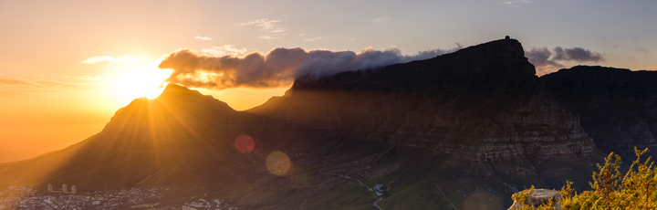 Eine spektakuläre Luftaufnahme des Tafelbergs in Kapstadt, Südafrika, bei Sonnenuntergang, mit der Stadt, die sich am Fuße des Berges ausbreitet und die Bucht überblickt.