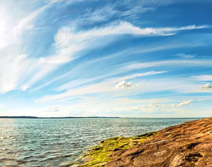 Eine Küstenlandschaft mit einem Strand und einem Leuchtturm, mit einem weiten Himmel.