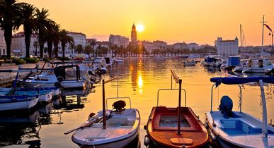 Ein Hafen in Split, Kroatien, mit Booten und Gebäuden bei Sonnenuntergang.
