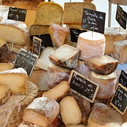 Eine Auswahl an verschiedenen Lebensmitteln, die auf einem Marktstand ausgestellt sind. Dazu gehören Oliven, Käse und andere lokale Spezialitäten, die appetitlich arrangiert sind.