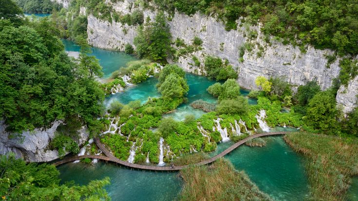 Ein großer Wasserfall, der in mehrere Stufen über Felsen fließt, umgeben von üppiger Vegetation.