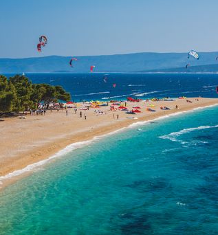 Ein Strand mit türkisfarbenem Wasser, umgeben von grüner Vegetation.