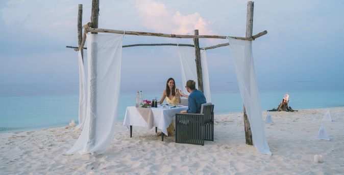 Junges Paar genießt Abendessen am Strand bei Sonnenuntergang auf den Malediven