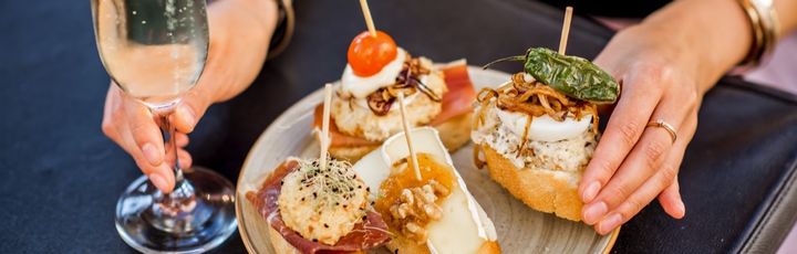 Eine Platte mit Tapas und einem Glas Wein.