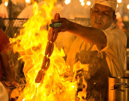 Mann grillt Spieß mit Würstchen über Feuer