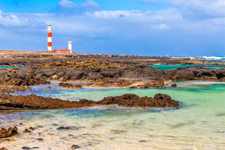 Leuchtturm hinter den Felsen und dem Meer.