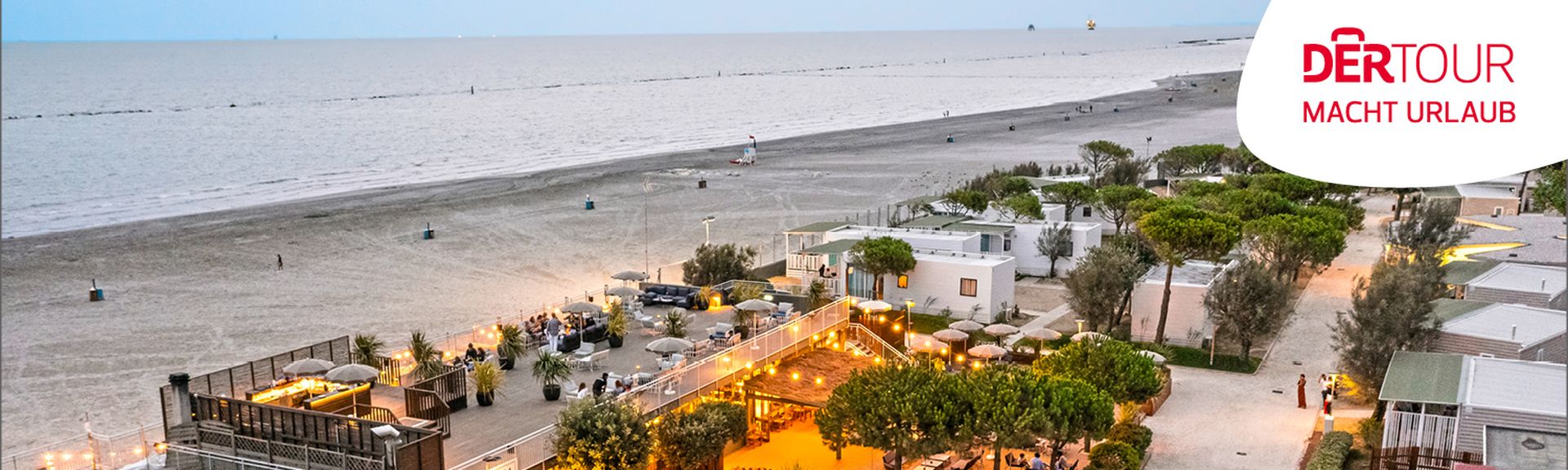 Panoramaaufnahme eines Campingplatzes am Strand mit Außenbereich und Restaurant bei Abendlicht.