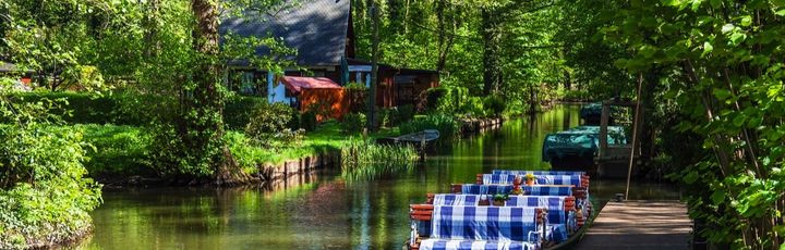 Ein traditioneller Spreewaldkahn gleitet durch die Kanäle des Spreewaldes, umgeben von üppigem Grün und dichten Wäldern.