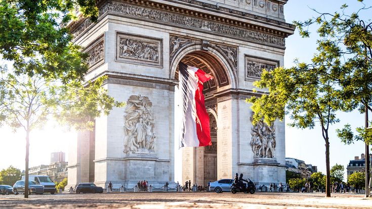 Der Arc de Triomphe in Paris, ein imposantes Denkmal mit einem Bogen und Skulpturen. Die Perspektive ist von unten, und der Bogen füllt den größten Teil des Bildes aus.