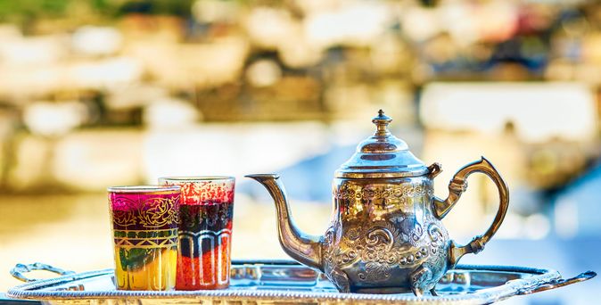 Eine silberne Kanne Tee und zwei Becher auf einem Balkon