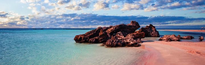 Ein rosa Sandstrand mit türkisfarbenem Wasser.