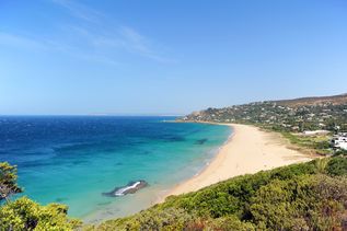 Heller Sandstrand an der Costa de la Luz in Spanien mit türkisem Meer und grünen Pflanzen 