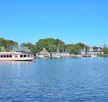 Eine Promenade am Müritzsee in Röbel mit Booten und Gebäuden am Ufer.