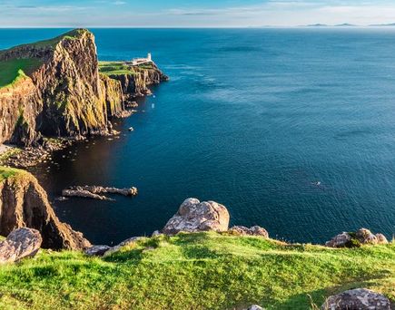 Eine felsige Insel mit einem Berg und einem alten Gebäude. Die Insel ist von blauem Wasser umgeben.